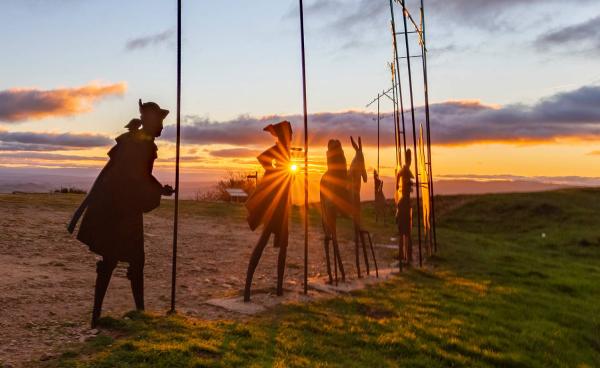 Image rétroéclairée d'une partie des sculptures de pèlerins à Alto del Perdón, au coucher du soleil